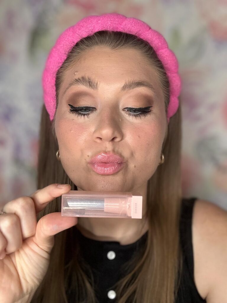 thesavannahk beauty blogger with pink padded headband, winged eyeliner and glossy lips, holding favorite lip gloss