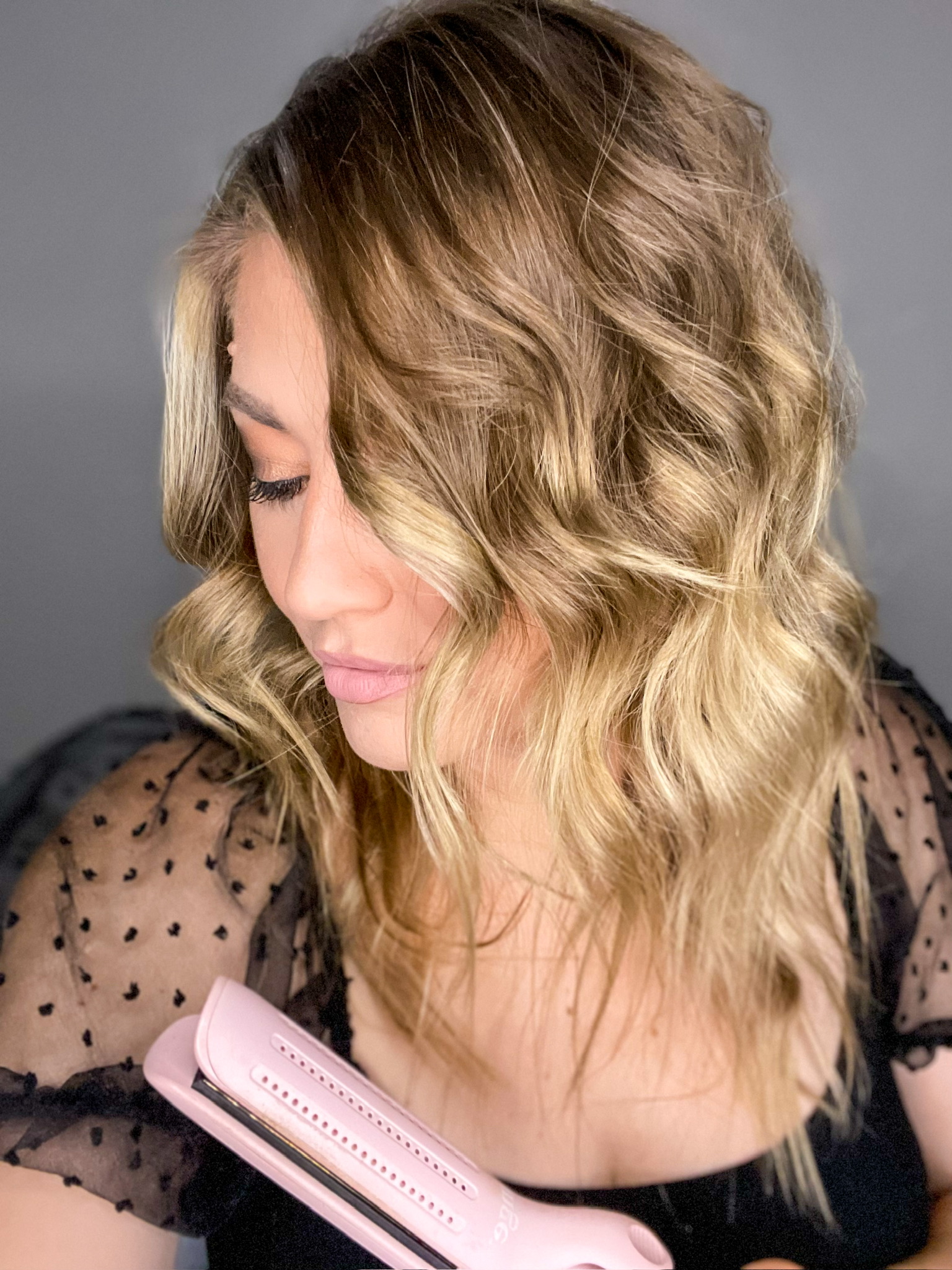 thesavannahk with blonde wavy hairstyle created using L’ange styling tool, soft glam makeup and sheer sleeve black top
