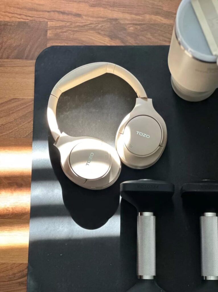Neutral home workout setup with headphones, dumbbells, and fitness mat, part of a busy mom wellness routine focused on sustainable weight loss and daily movement.